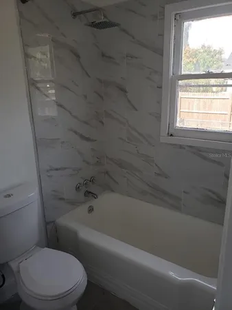 a white toilet and tub sitting next to a window