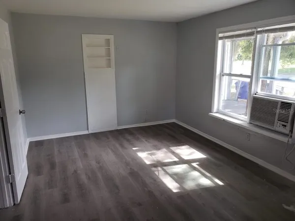 a view of empty room with wooden floor and fan