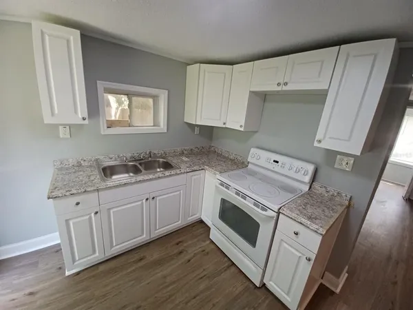 a kitchen with granite countertop white cabinets and white appliances