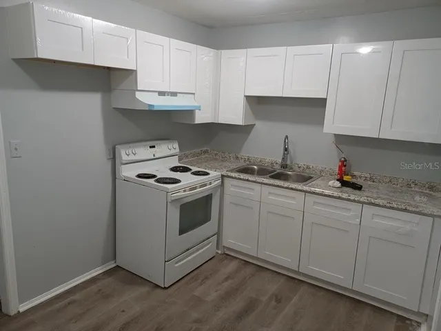 a kitchen with granite countertop white cabinets and white appliances