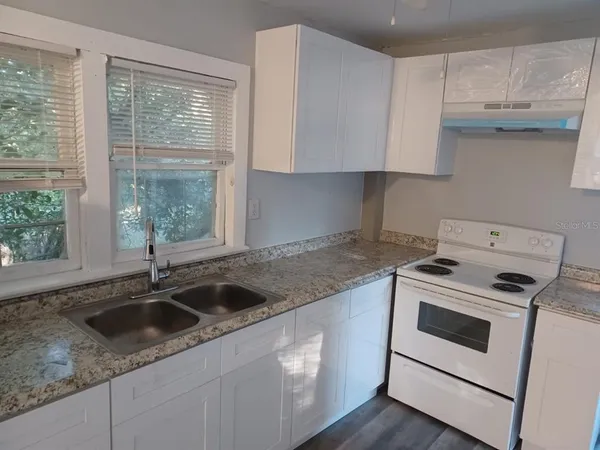 a kitchen with granite countertop white cabinets and a sink