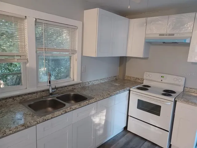 a kitchen with granite countertop white cabinets and a sink
