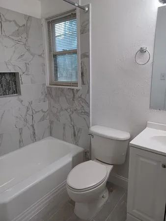 a white toilet sitting next to a bath tub