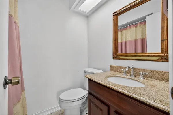 a bathroom with a granite countertop sink toilet and mirror