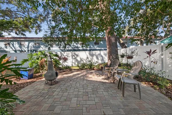 a view of a patio with table and chairs potted plants and large tree