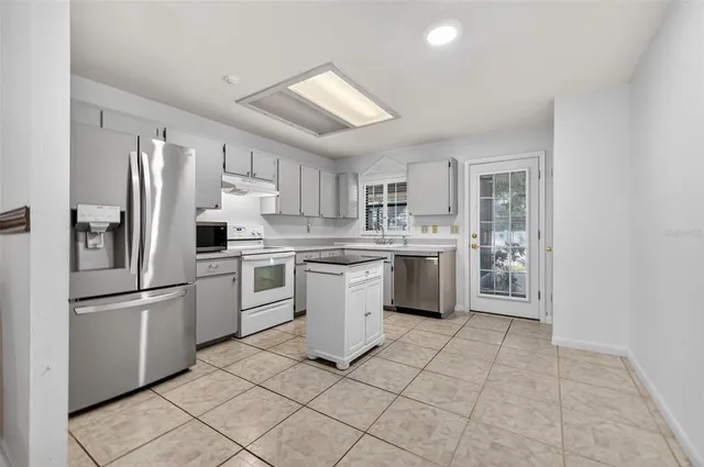 a kitchen with white cabinets stainless steel appliances and a refrigerator