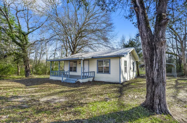 a front view of a house with a yard deck and large tree