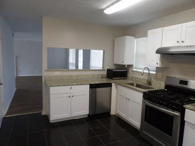 a kitchen with granite countertop white cabinets and stainless steel appliances