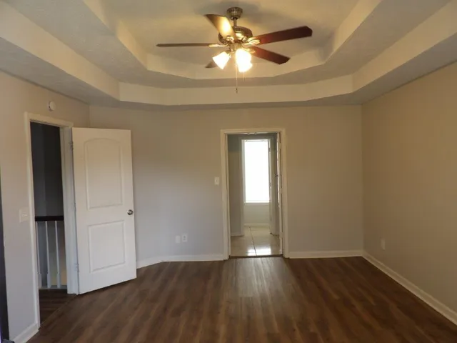 an empty room with wooden floor and a ceiling fan