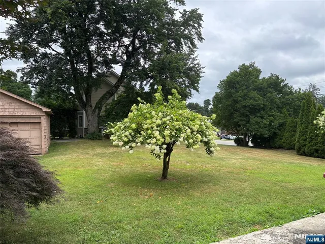 a view of yellow house with a big yard and large trees
