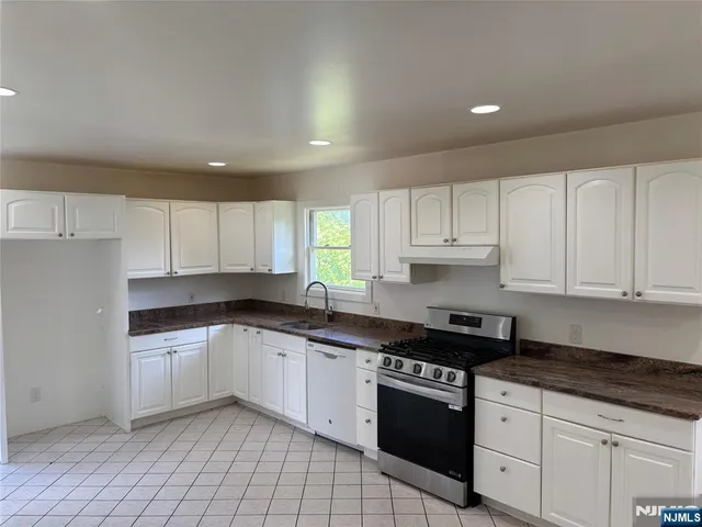 a kitchen with granite countertop a sink a stove and cabinets