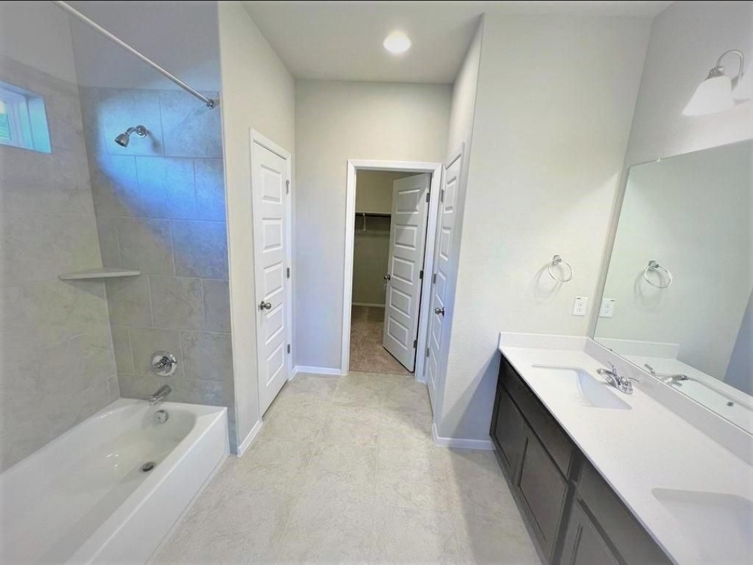 2771 Winding Creek Road Kyle, TX 78640 - Photo 11 of 24 A well-appointed bath features a double vanity and sleek tub-shower combination, creating a functional space.