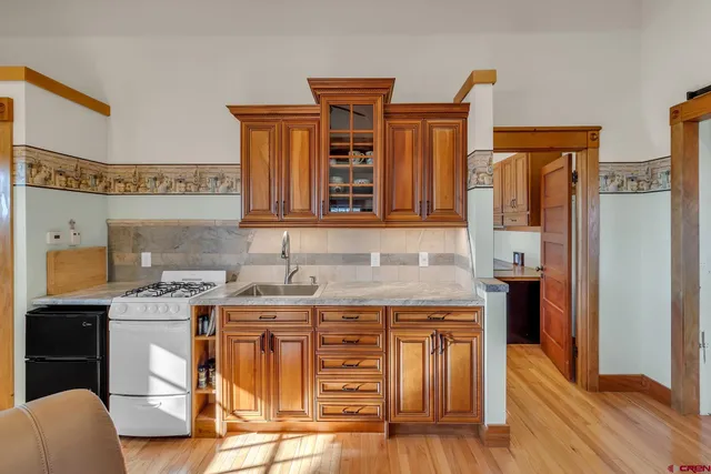 a kitchen with a refrigerator a sink and wooden floor
