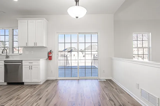 a kitchen with granite countertop a stove a sink and white cabinets with wooden floor next to windows