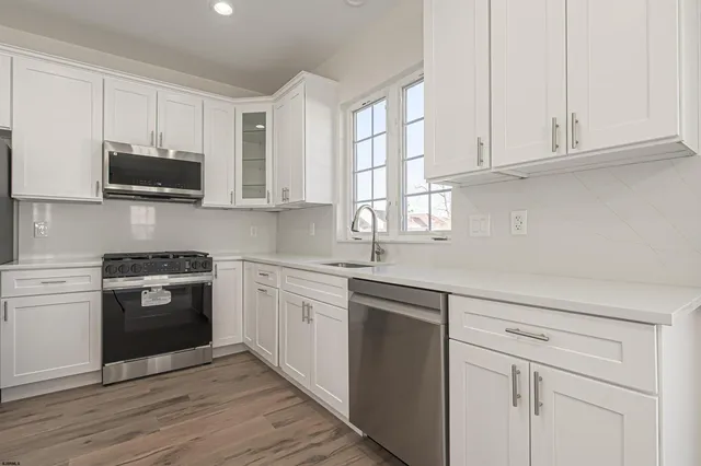 a kitchen with stainless steel appliances granite countertop a stove a sink and white cabinets