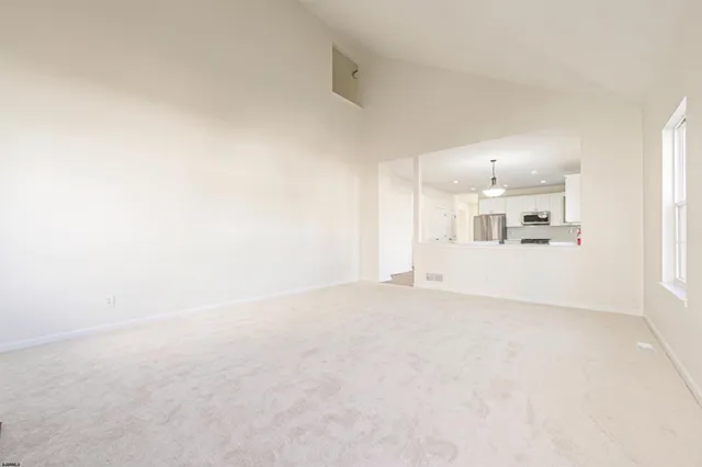 a view of a white wall with kitchen view and wooden floor