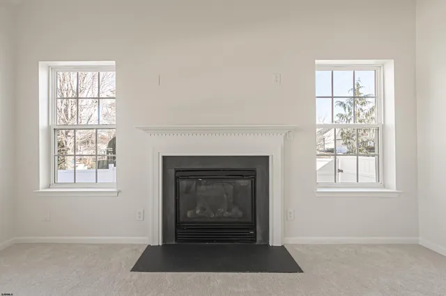 an empty room with windows and fireplace