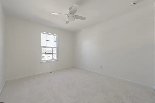 an empty room with a window and ceiling fan