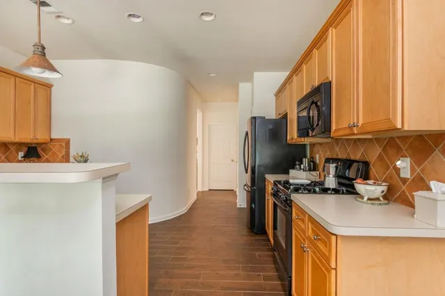 a kitchen with stainless steel appliances a sink a stove a refrigerator cabinets and a window