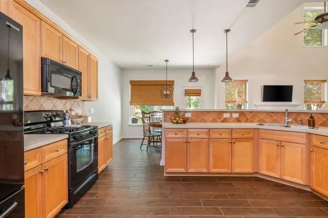 a large kitchen with stainless steel appliances kitchen island granite countertop a stove top oven a sink a dining table and chairs