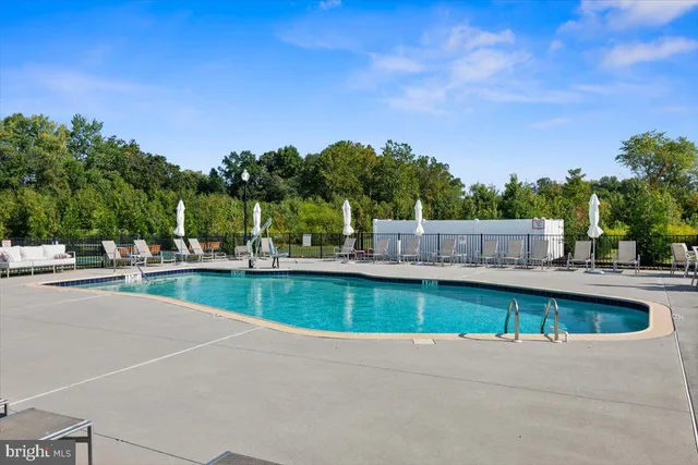 a view of swimming pool with seating area and trees in the background