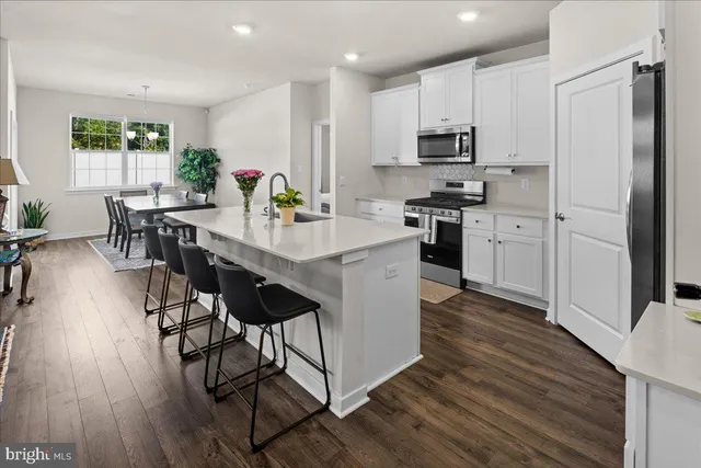 a kitchen with stainless steel appliances a dining table chairs stove refrigerator and microwave