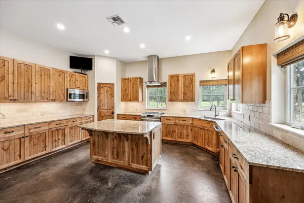 a large kitchen with stainless steel appliances granite countertop a stove and large wooden cabinets