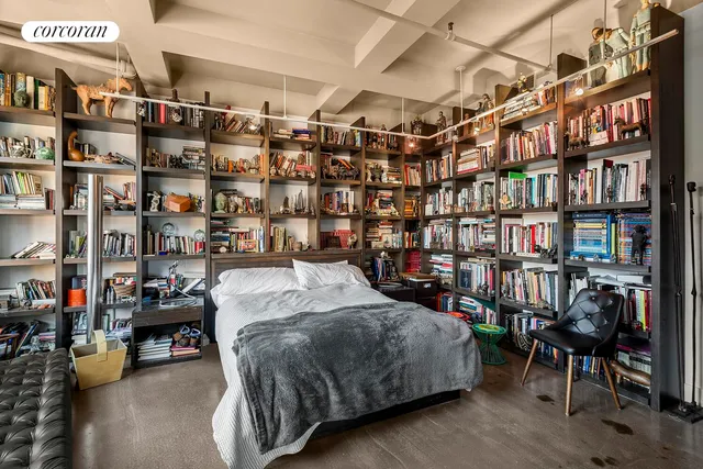 a bed sitting in a bedroom next to a book shelf