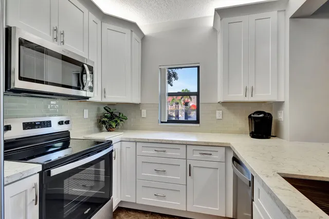 a kitchen with stainless steel appliances granite countertop a stove a refrigerator and a microwave