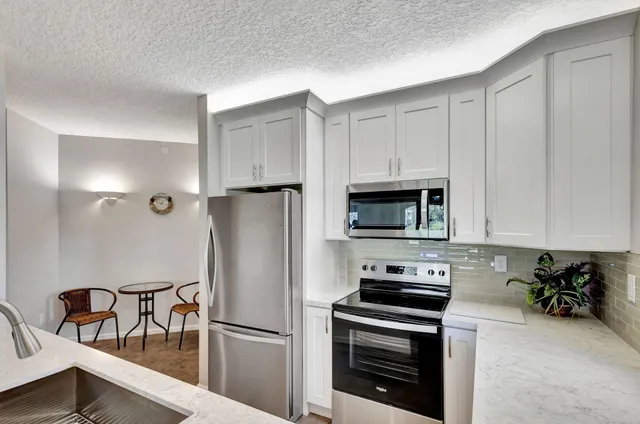 a kitchen with stainless steel appliances white cabinets and chandelier