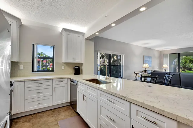 a kitchen with granite countertop white cabinets and stainless steel appliances