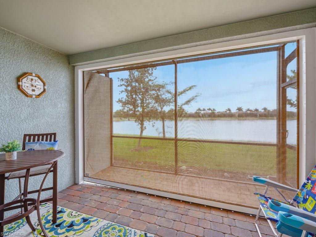 14591 Edgewater Circle Naples, FL 34114 - Photo 15 of 36 Screened lanai featuring a lake view showing hurricane shade in place to protect furniture during inclement weather