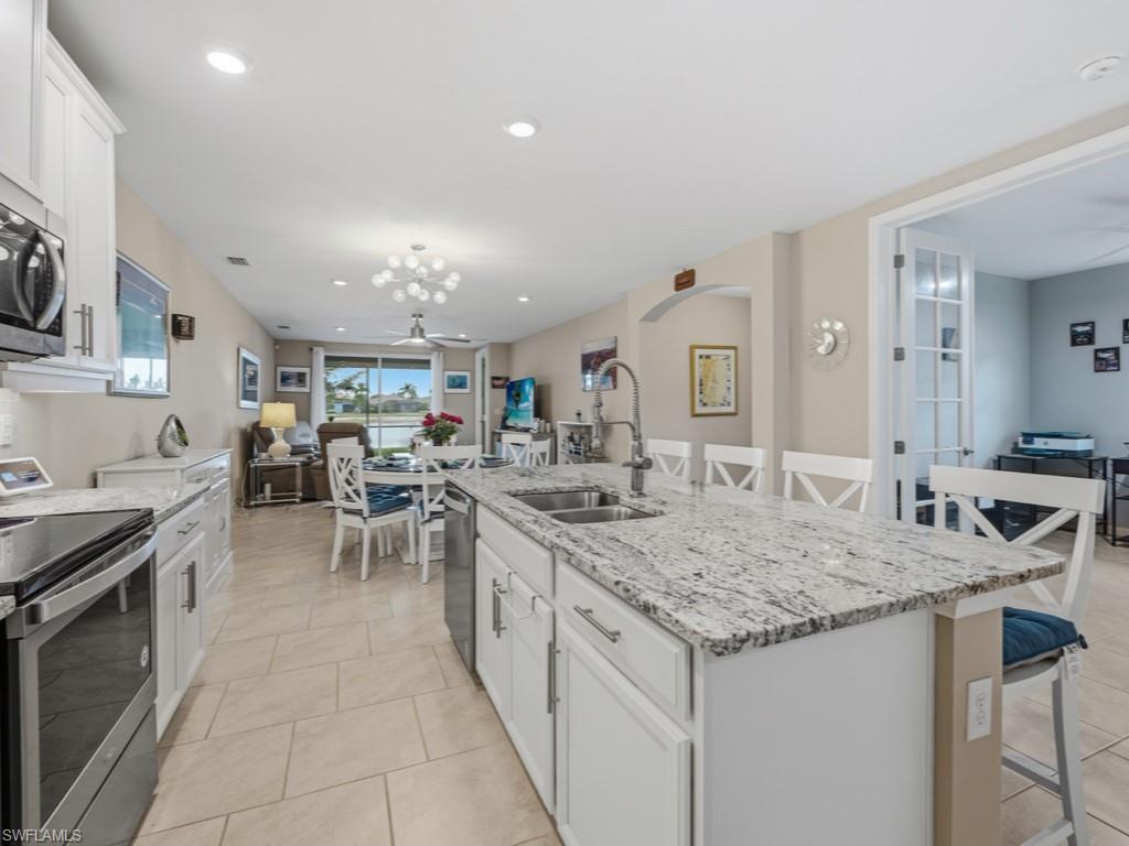 14591 Edgewater Circle Naples, FL 34114 - Photo 3 of 36 Kitchen featuring white cabinets, a kitchen breakfast bar, stainless steel appliances, and recessed lighting