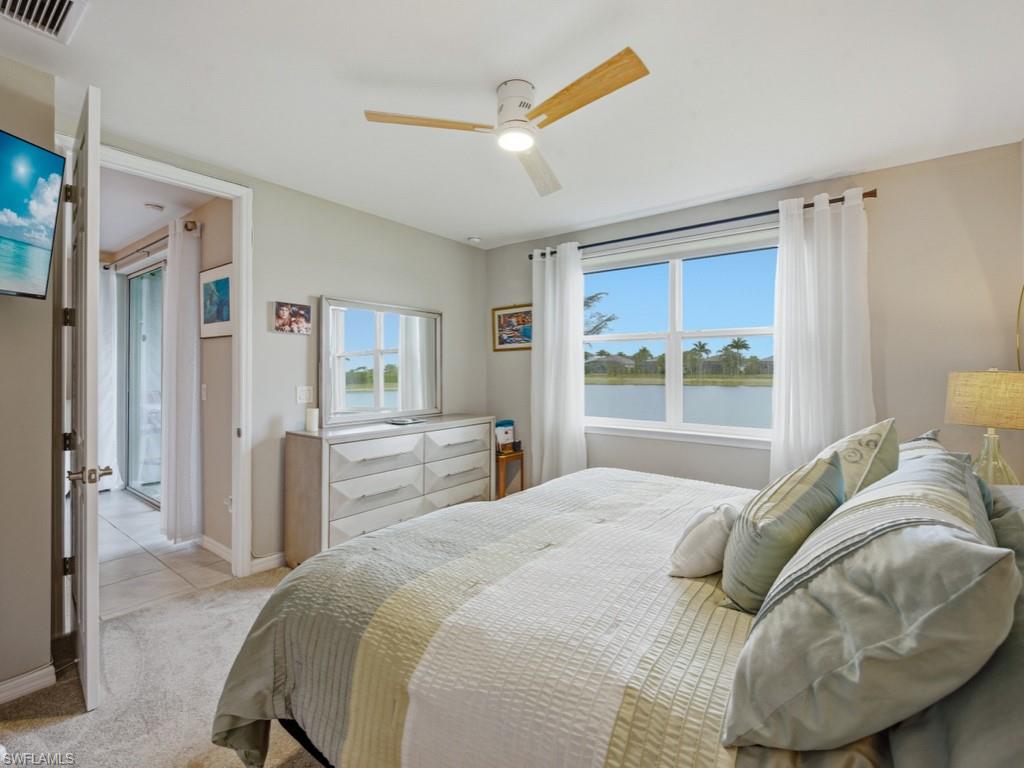 14591 Edgewater Circle Naples, FL 34114 - Photo 9 of 36 Bedroom featuring a water view, a ceiling fan with light, and brand new carpet just installed-furniture conveys including two lamps and two round mirrors