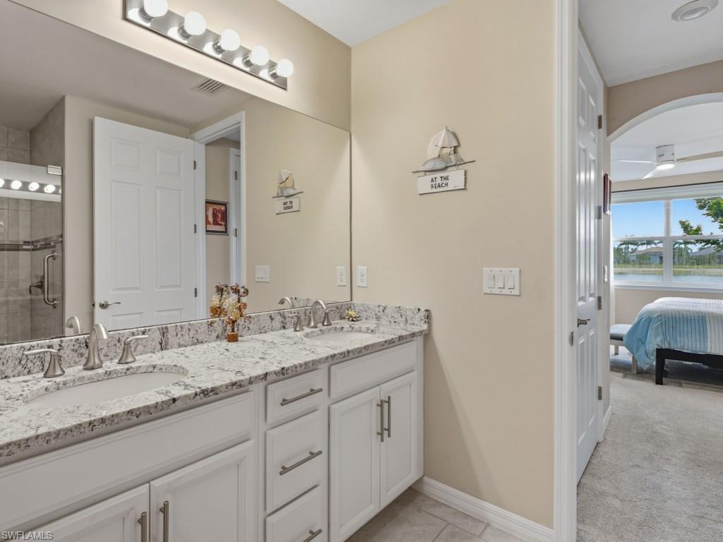 14591 Edgewater Circle Naples, FL 34114 - Photo 10 of 36 Full bath featuring double vanity, ensuite bathroom, matching tile, and a tile shower with grab bars for safety