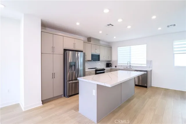 a large kitchen with stainless steel appliances a sink a refrigerator and a stove