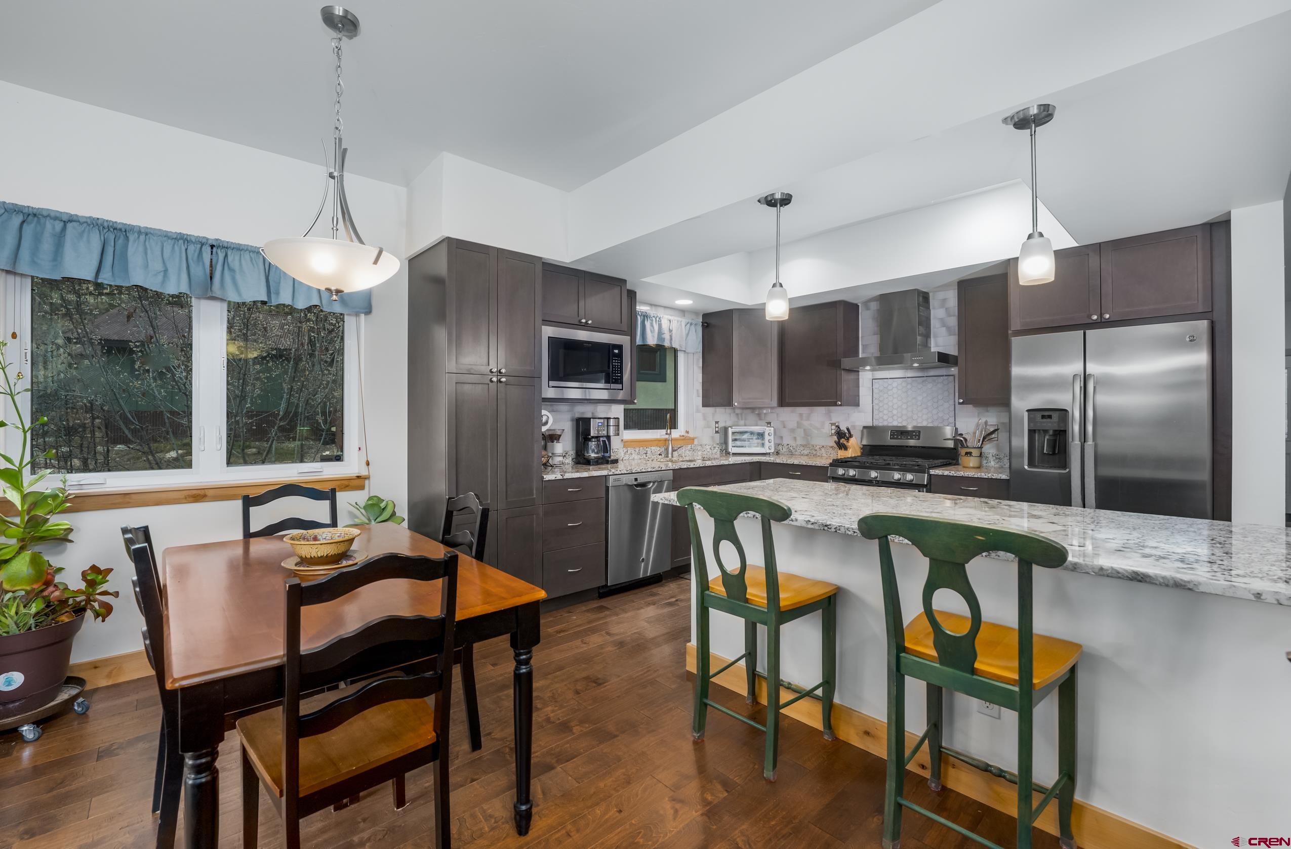 41 Mountain Stream Court Durango, CO 81301 - Photo 21 of 29 a kitchen with stainless steel appliances granite countertop a refrigerator a stove a sink a dining table and chairs with wooden floor