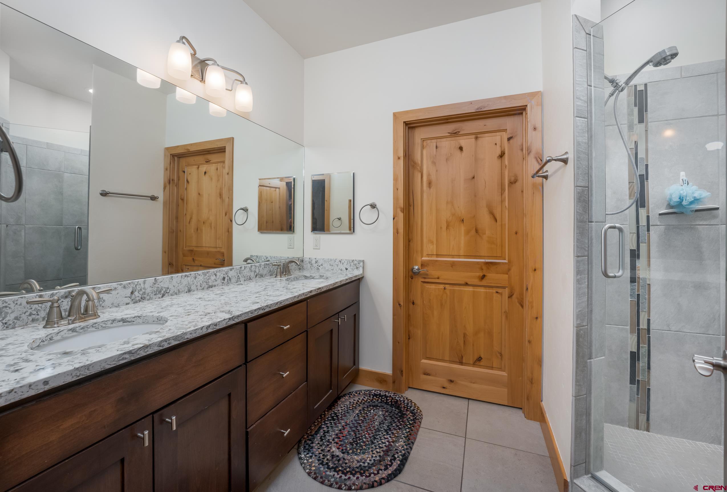 41 Mountain Stream Court Durango, CO 81301 - Photo 9 of 29 a bathroom with a granite countertop sink a mirror a vanity and a shower