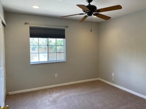 an empty room with a window and a fan