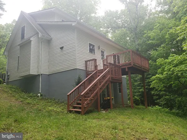 a view of a house with a yard and a wooden deck