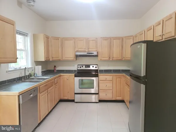 a kitchen with granite countertop white cabinets and refrigerator