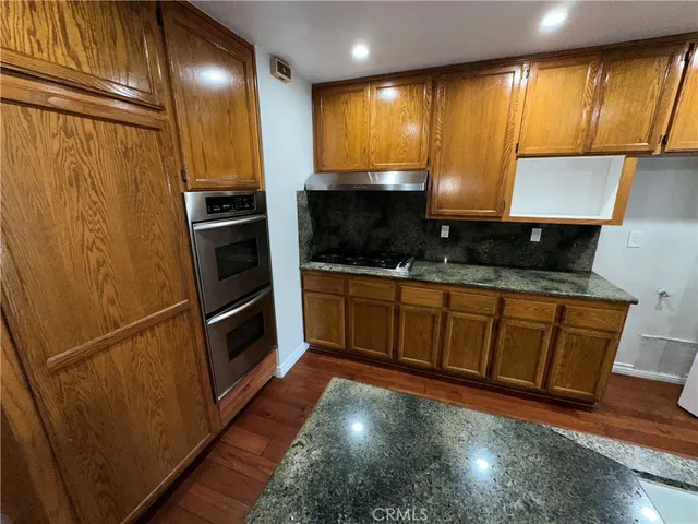a kitchen with stainless steel appliances granite countertop a refrigerator a sink and a stove