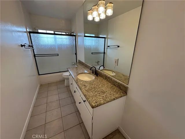 a bathroom with a granite countertop sink a toilet a mirror and shower