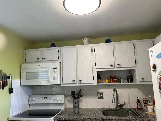 a kitchen with white cabinets and window