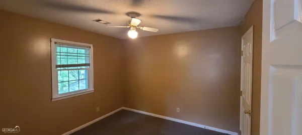 an empty room with windows and chandelier fan
