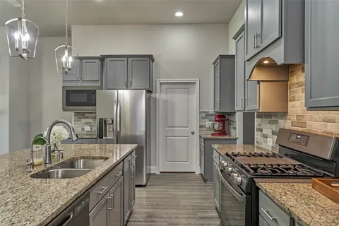 a kitchen with granite countertop a sink stainless steel appliances and cabinets