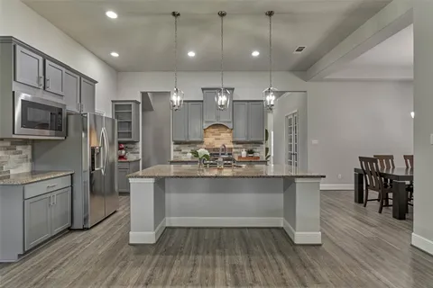 a view of a kitchen with kitchen island a counter top space stainless steel appliances and wooden floor