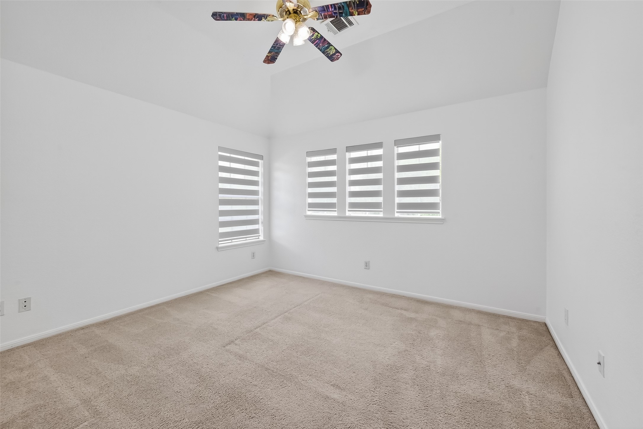 1311 Rene Court Sugar Land, TX 77479 - Photo 41 of 45 Bright, spacious room with neutral carpeting, white walls, and modern window treatments. Features a ceiling fan with colorful blades, adding a touch of character.