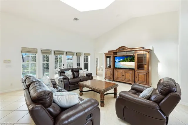 a living room with furniture a flat screen tv and a floor to ceiling window