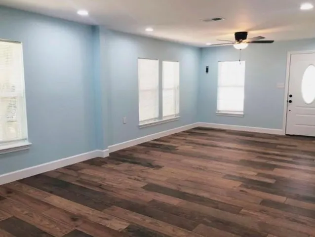 an empty room with wooden floor and windows
